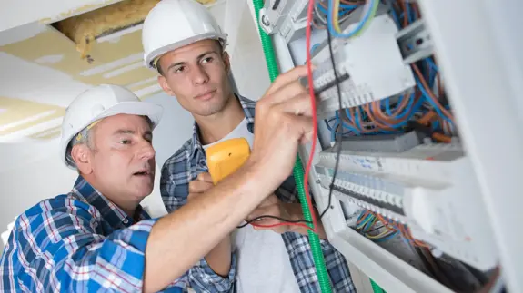 Man And Apprentice Installing A Distribution Board